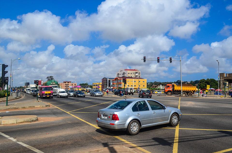 Traffic at a signalised junction on an Accra highway under a bright sky